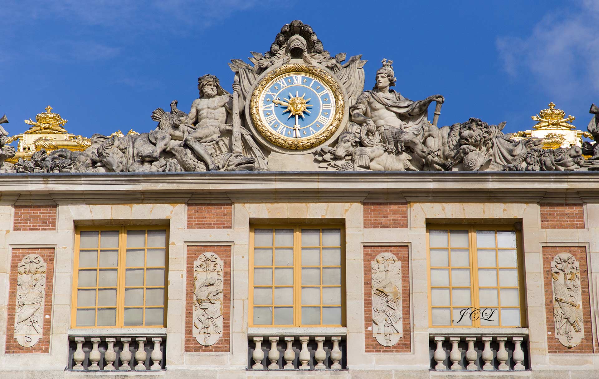 L'horloge de la cour de marbre du Chateau de Versailles. Elle est encadrée d'un tore de laurier, sommée d'un casque et flanquée d'étendards.